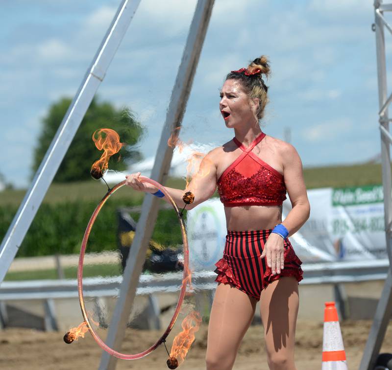 A performer with the Cincinnati Circus Thrill Show uses a burning hula hoop as part of her fire act at the Lee County Fair on Sunday, July 30, 2023.
