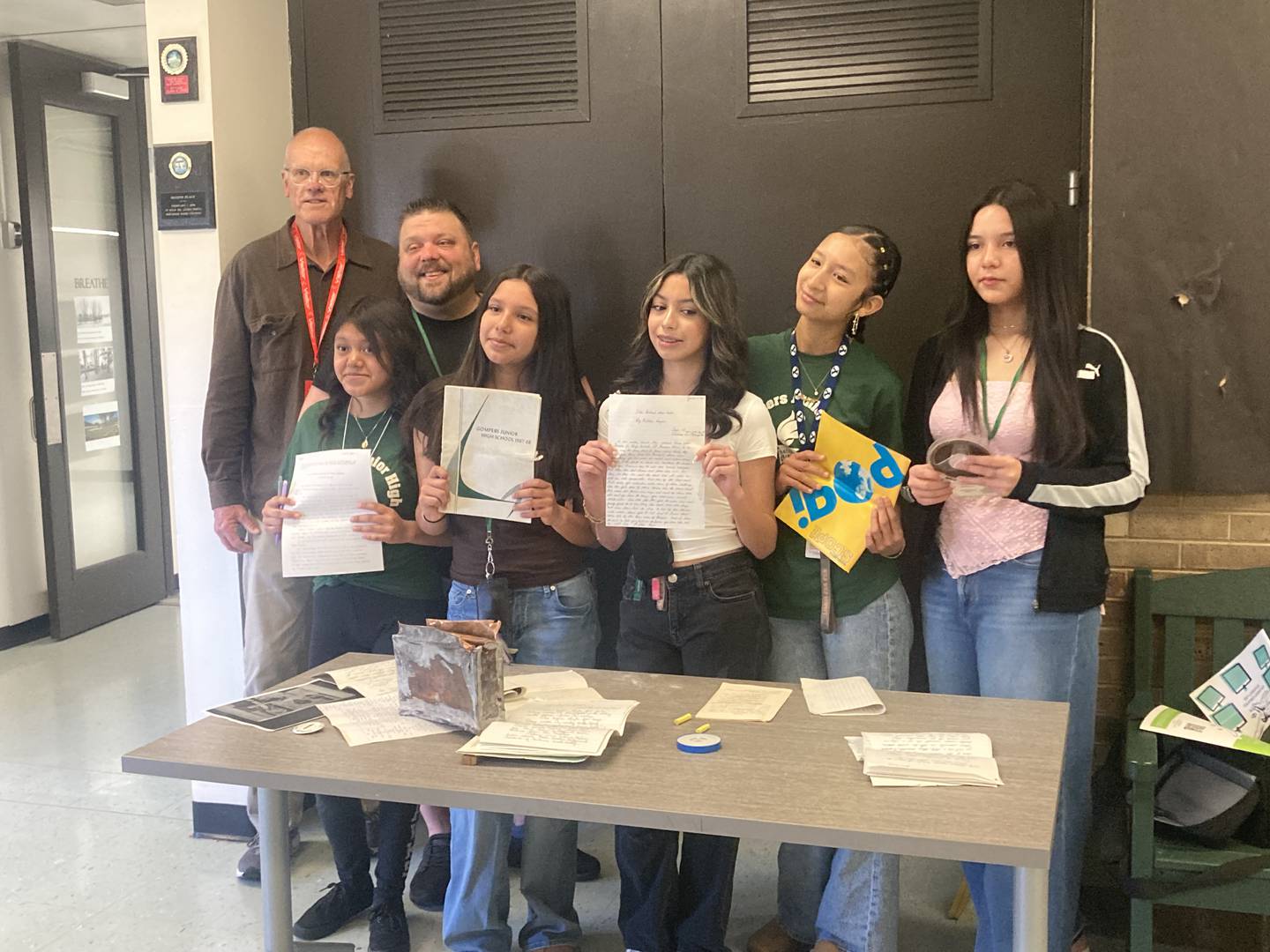 Gompers Junior High students Alisson Gaitan Lopez, Evelyn Carrillo, Jocelyn Lopez, Isabella Salgado, and Isabella Campos stand with their teacher Chad Nelson, and Gompers Alum Larry Nielson with objects from the 1969 time capsule on Friday, May 1, 2026.