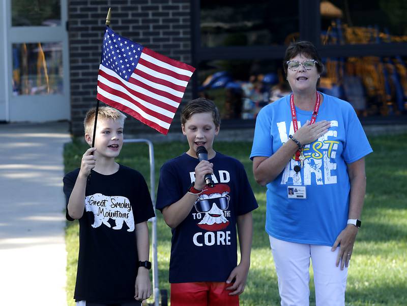Colton Titley delivers the “Pledge of Allegiance” with Principal Beth Klinsky, while Jack Hunter holds the American Flag, during the first day of school at West Elementary School in Crystal Lake on Wednesday, Aug. 16, 2023.