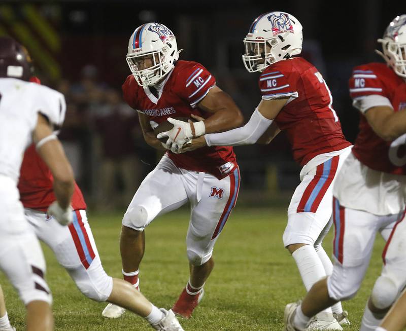 Marian Central's Cale McThenia hands the ball off to Christian Bentancur during a nonconference football game against Richmond-Burton Friday, Aug. 25, 2023, at Marian Central Catholic High School.