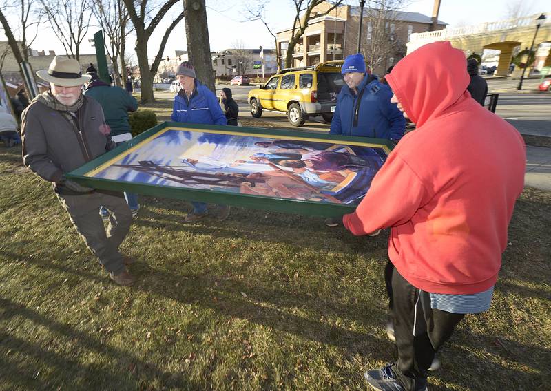 Volunteers walk one of the 16 paintings depicting the life of Christ to it’s correct location Saturday in Ottawa’s Washington Square