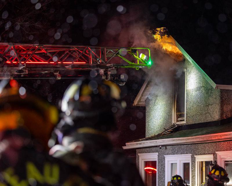 Firefighters standing outside front door of a '2nd Alarm' house fire point towards flame on Saturday, January 10, 2026, at 217 West Delvin Street in Spring Valley.