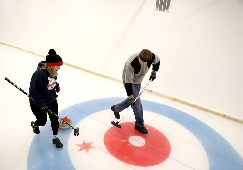 Sweepers Donna Wood of Lisle and Jeff Utterback of Sugar Grove control the trajectory of the stone down the sheet of ice during a drop-in game of Curling at the Windy City Curling Club in Villa Park.