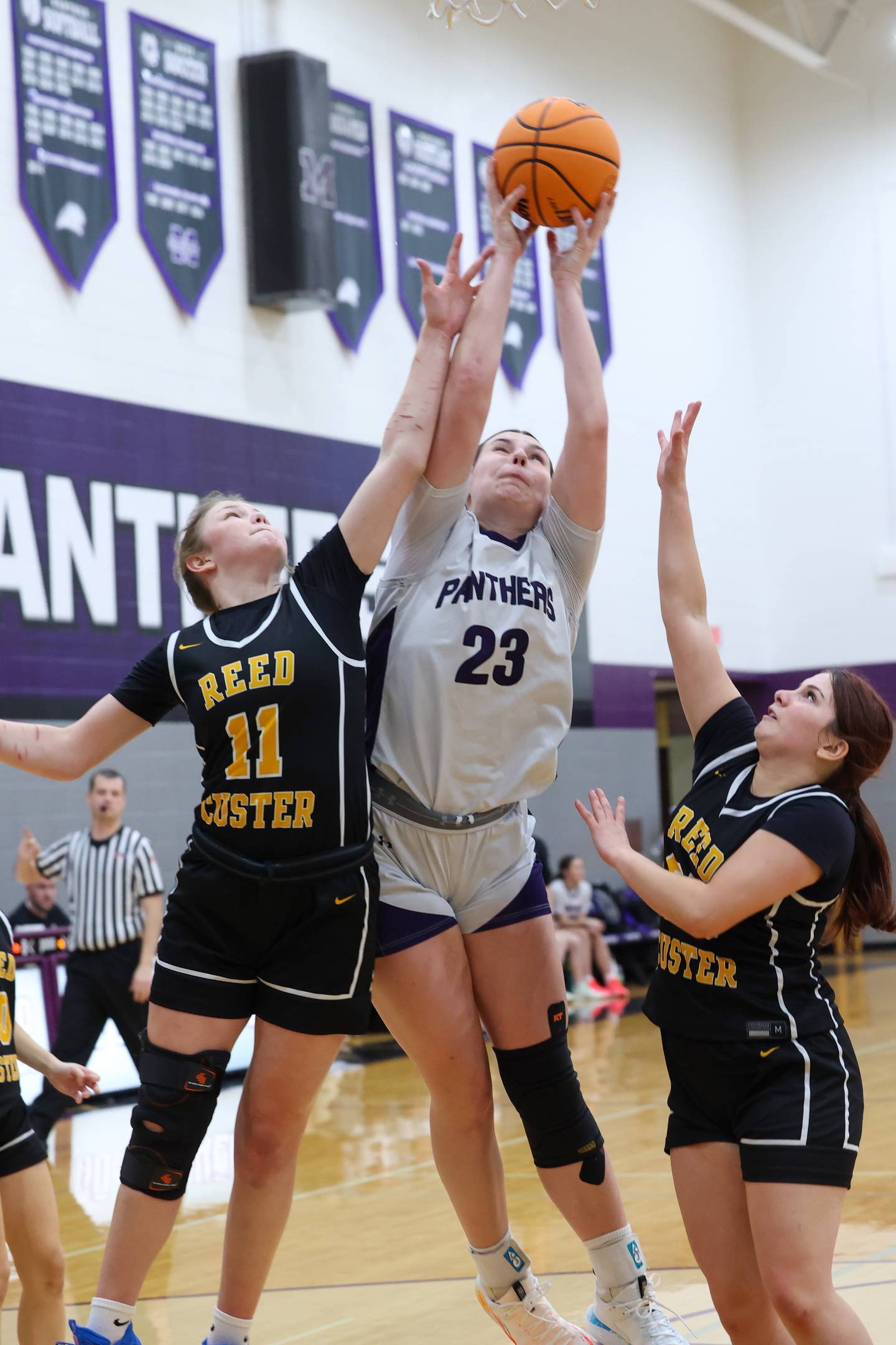 Manteno's Maddie Gesky reaches to secure a rebound against Reed-Custer's Morgan Toler, left, and Brooklyn Gonzalez during Reed-Custer's 45-42 victory over Manteno on Monday, Feb. 2, 2026.