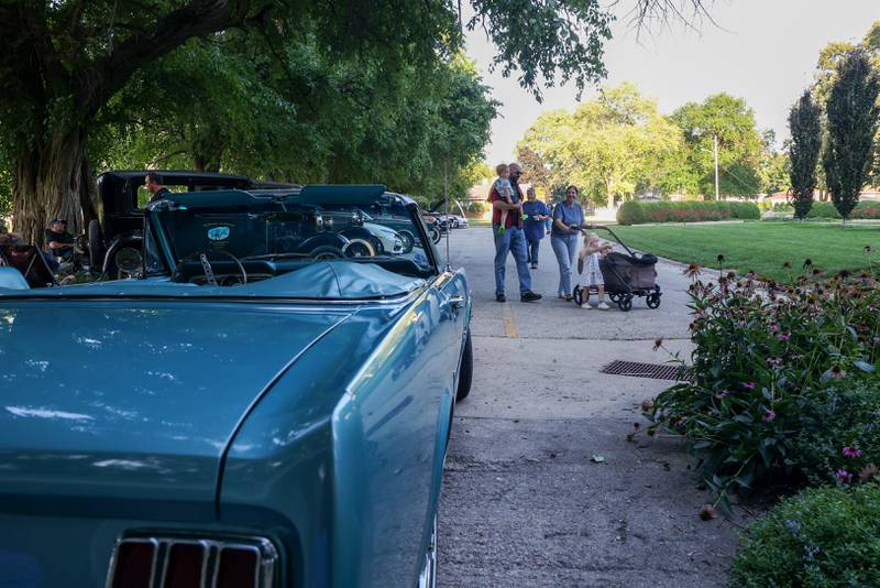 A family arrives to view some 30 cars on display, including the 1966 Ford Mustang in the color Tahoe Turquoise, owned by Bill Cheffer, of Kankakee, during the Cruise-In Night at the Museum on Thursday, Aug. 14, 2025.