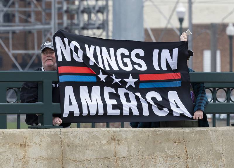 Protestors line the edges of the Galena Avenue bridge in Dixon Saturday, April 19, 2025, voicing their opinion of President Trump and their feelings the administration is not following a Democracy based government.