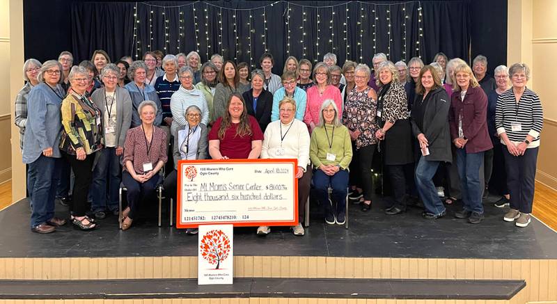 Mt. Morris Senior Center Executive Director Melissa Rojas (center) smiles as she poses with members of the 100 Women Who Care of Ogle County and the mock check representing the $8,600 donation given to the center on April 18, 2024.