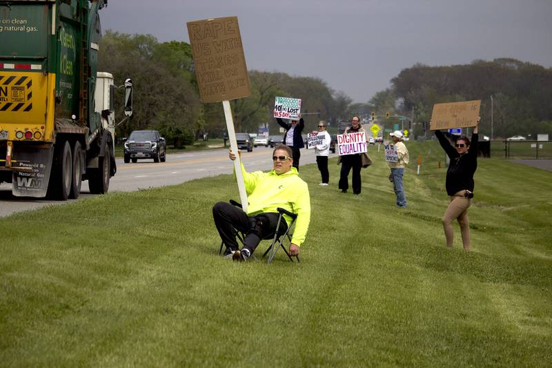 People hold up signs on Thursday, May 1, 2025, for a democracy rally in Joliet with signs critical of U.S. President Donald Trump. More than 20 people attended the rally held near the busy West Jefferson Street and the Joliet Regional Airport.