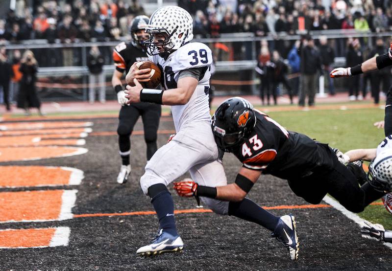 Cary-Grove's Tyler Pennington runs pass Libertyville's Abe Durrani while scoring a touchdown during the second quarter of Saturday's Class 7A semifinal game in Libertyville November 22, 2014. Cary-Grove won, 41-7.