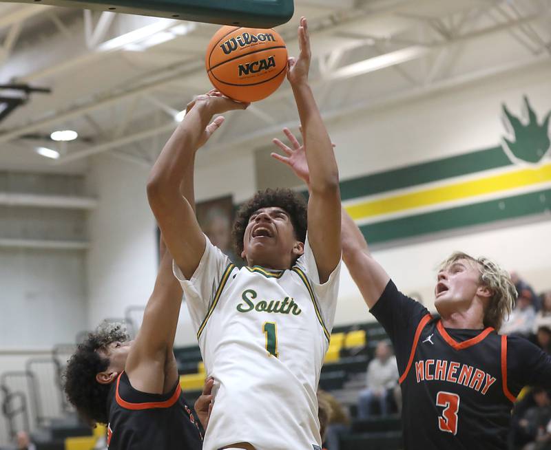 Crystal Lake South's Noah Cook shoots the ball between McHenry's Adam Anwar (left) and Dane Currie (right) during a Fox Valley Conference boys basketball game on Wednesday, Jan. 14, 2026, at Crystal Lake South High School.