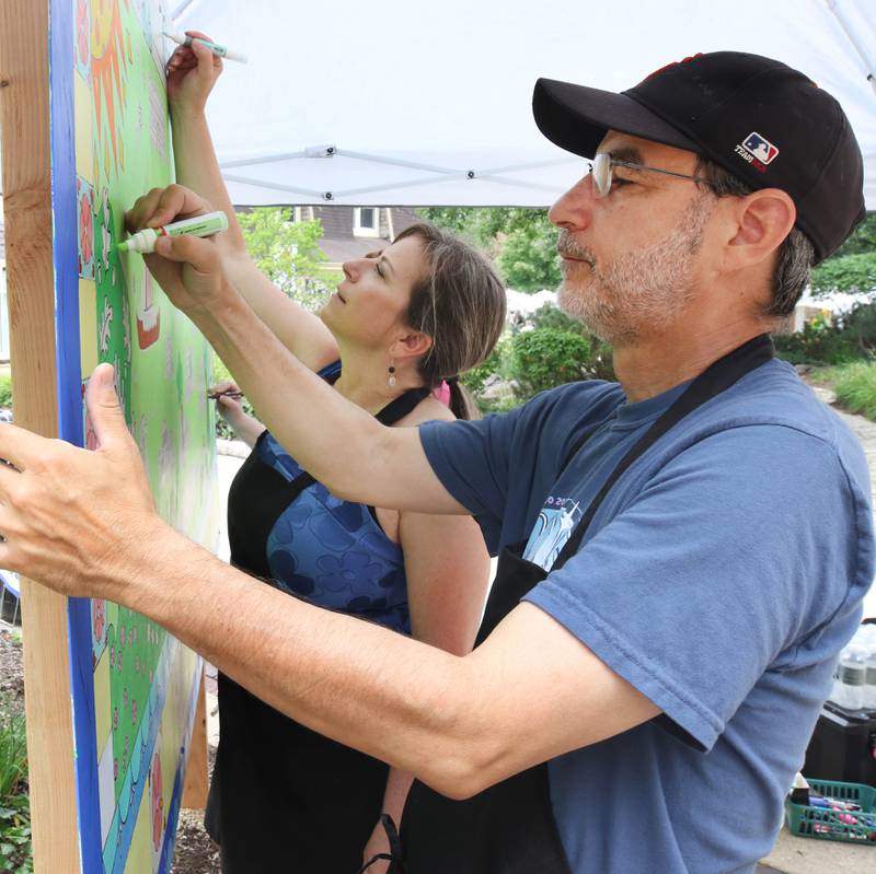 Sandy Kresler (left) and Mike Litwin, both from Geneva, work on the Geneva Chamber of Commerce’s paint-by-number community art project Saturday, July 26, 2025, during at the Geneva Arts Fair on Third Street in Geneva.