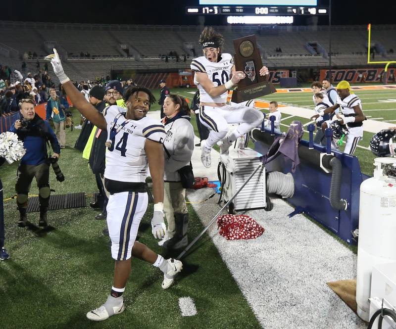 IC Catholic's Nico Palmieri (50) leaps over the team bench as teammate Jayden Sutton (54) watches after winning the the Class 3A State Championship on Friday, Nov. 25, 2022 at Memorial Stadium in Champaign.