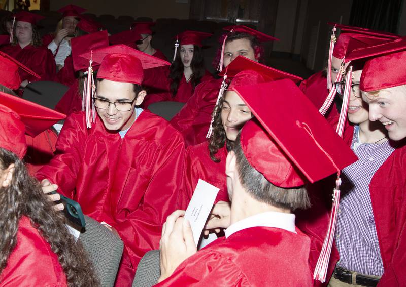 John Klag watches The SpongeBob Movie on his phone while waiting in the Ottawa High School auditorium for the commencement ceremony Friday, May 27, 2022.