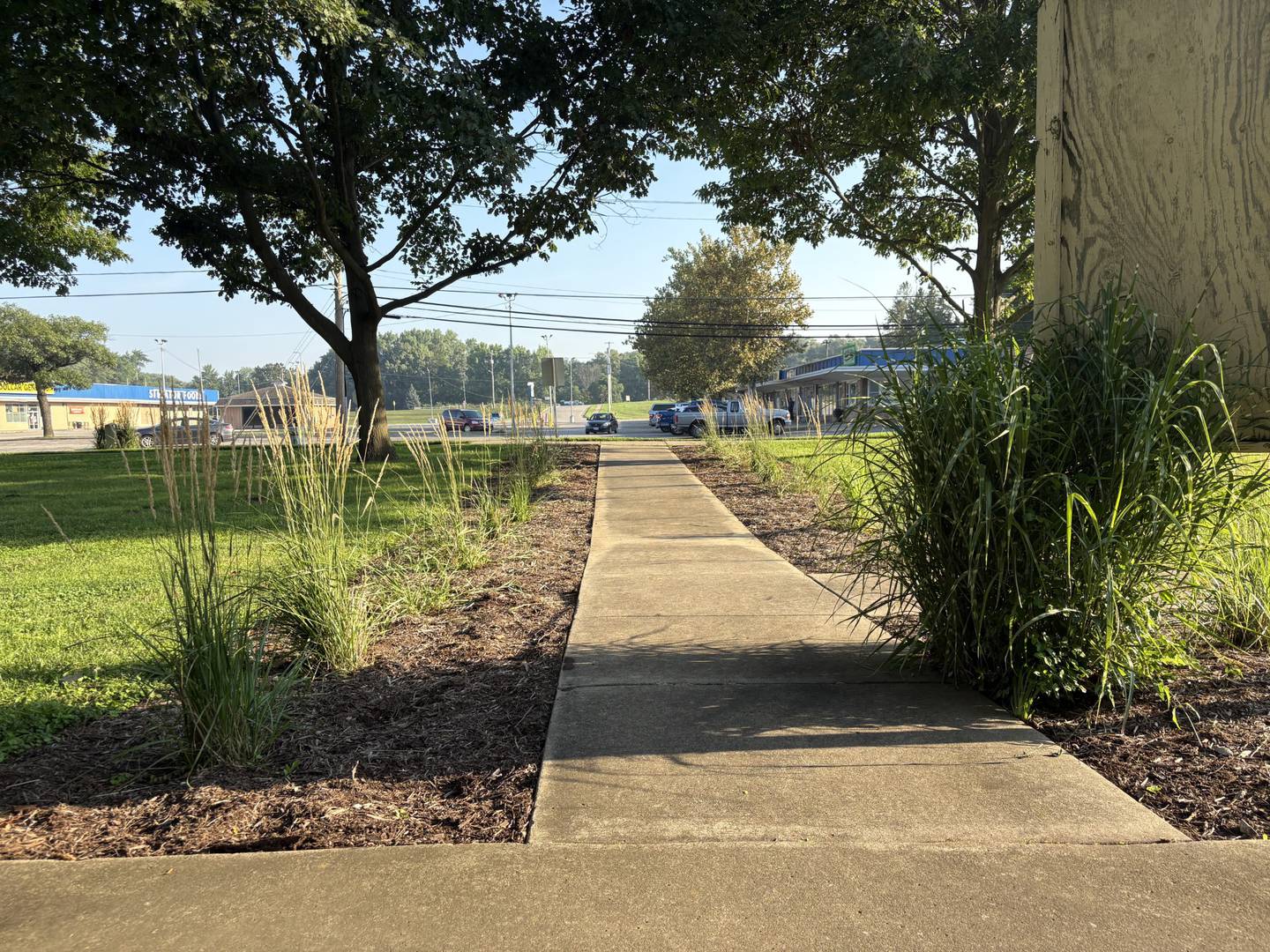 A newly cleared flower bed and trimmed native grasses line the sidewalk leading up to the playground at Merriner Park in Streator.