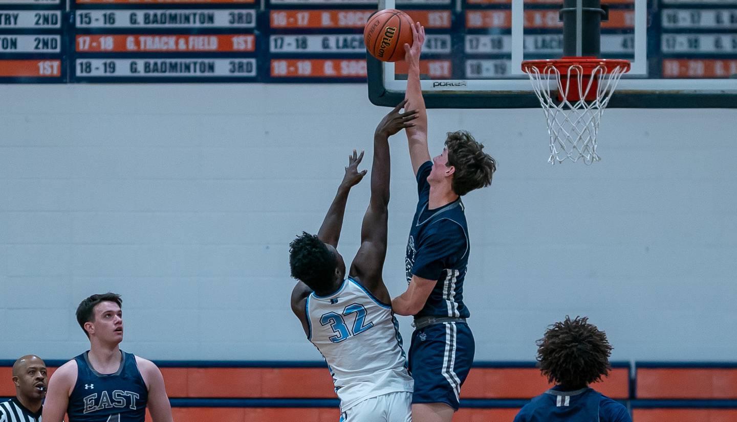 Oswego East's Ryan Johnson (12) blocks a shot by Downers Grove South's Brandon Amaniampong (32) during the hoops for healing basketball tournament at Naperville North High School on Monday, Nov 21, 2022.