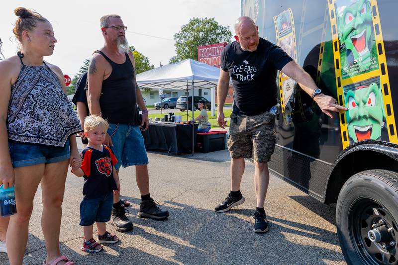 Guide shows family a photo of a prop used in the movie "Maximum Overdrive" on Saturday, August 9, 2025 at the annual Wenona Days on Chestnut Street in Wenona.