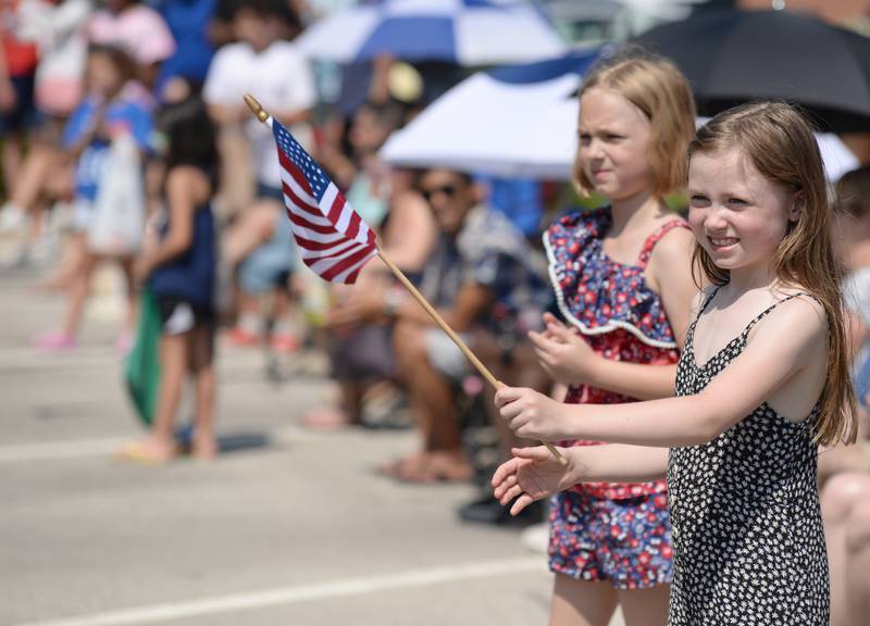 Eliza Gabriel (left) of Clarendon Hills and Alexis Hildebrand of Westmont wave to participants of  the Hinsdale 4th of July parade Tuesday June 4, 2023.