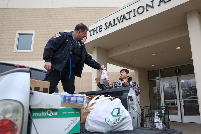 Officer John Perri hands food donations to a Salvation Army volunteer from the police department’s “Pack the Paddy Wagon” food drive at the Salvation Army in Joliet.