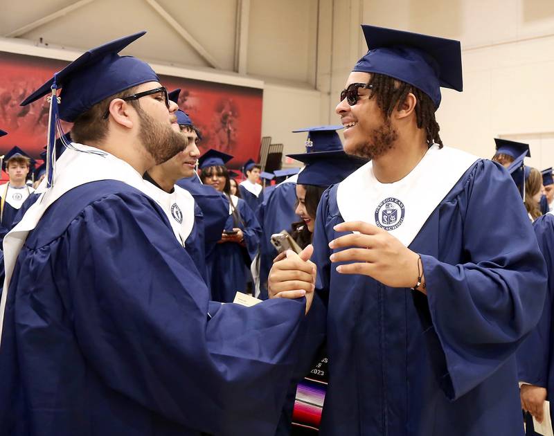 Oswego East graduates Juan Ortiz and Oshobi Odior congratulate each other on Saturday, May 20, 2023 in DeKalb.