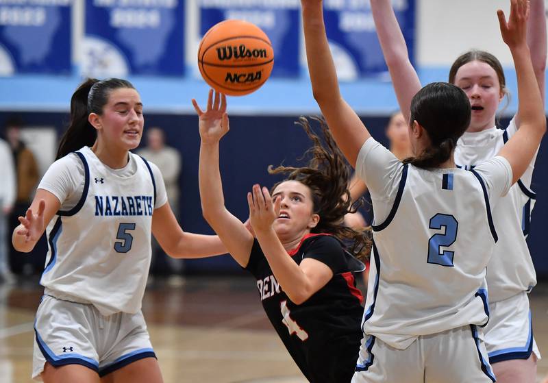 Benet’s Ava Mersinger (4) throws the ball toward the basket after a foul as she falls between Nazareth’s Sophia Towne (5) and Samantha Austin (2) during a game on December 13, 2025 at Nazareth Academy in LaGrange Park.