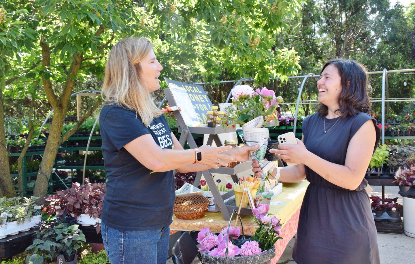 Diana Merry of Sterling, right, purchases peonies from Nancy Perrotta, left, owner of Little Red Truck Apiary, during at the Sycamore farmers market Tuesday.