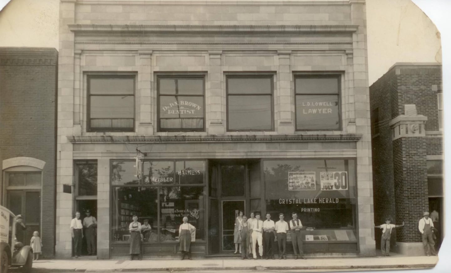 John Heisler Sr., with arms folded (left), standing outside his shop at 83 E. Woodstock St., Crystal Lake in the early 1900s.
