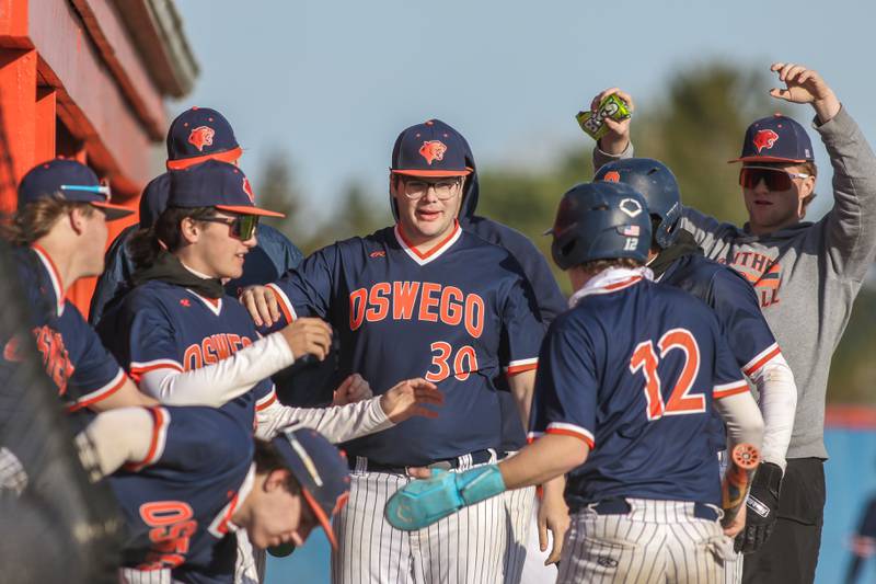 Oswego's Quinn Stanley (12) is greeted in front of the dugout after scoring a run during baseball game between Plainfield South at Oswego on Monday, April 14, 2025 in Oswego.