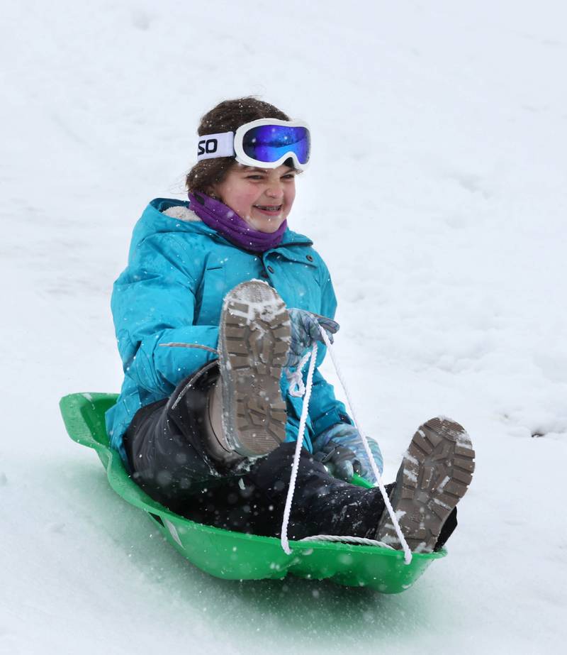 Olivia Weller, 9, from DeKalb, flys down the sled hill Tuesday, Jan. 9, 2024, at Hopkins Park in DeKalb. Several inches of heavy, wet snow Tuesday was a headache for some and fun for others.