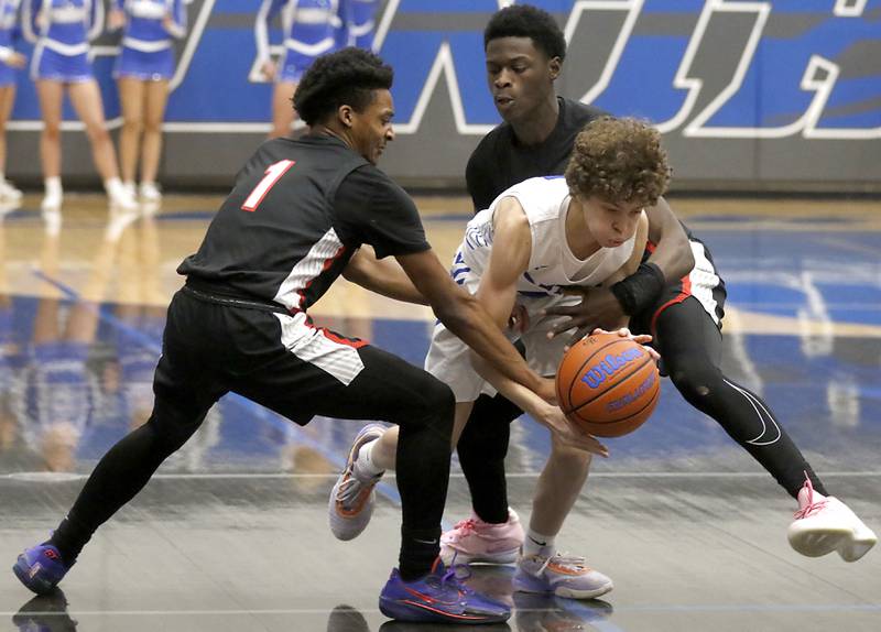 Huntley's Bryce Walker(left) and  Jeffrey Cruickshank (right) try to steal the ball from Burlington Central's Ryan Carpenter during a Fox Valley Conference boys basketball game on Friday, Dec. 15, 2023, at Burlington Central High School.