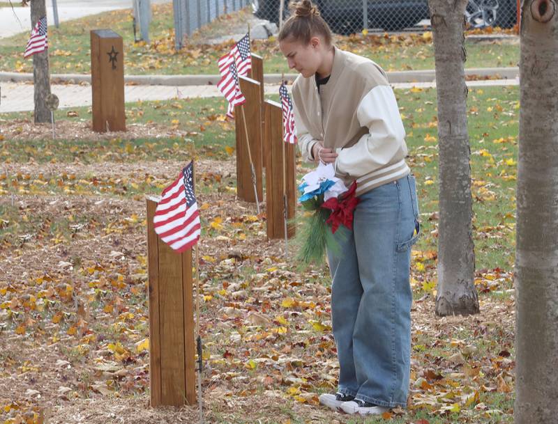 Sydney Mautino, a student at Hall High School, places a patriotic decoration at the site to commemorate the fallen 24 soldiers who attended Hall High School that died in WWII during the Veterans Day program on Tuesday, Nov. 11, 2025 in t Hall High School.
