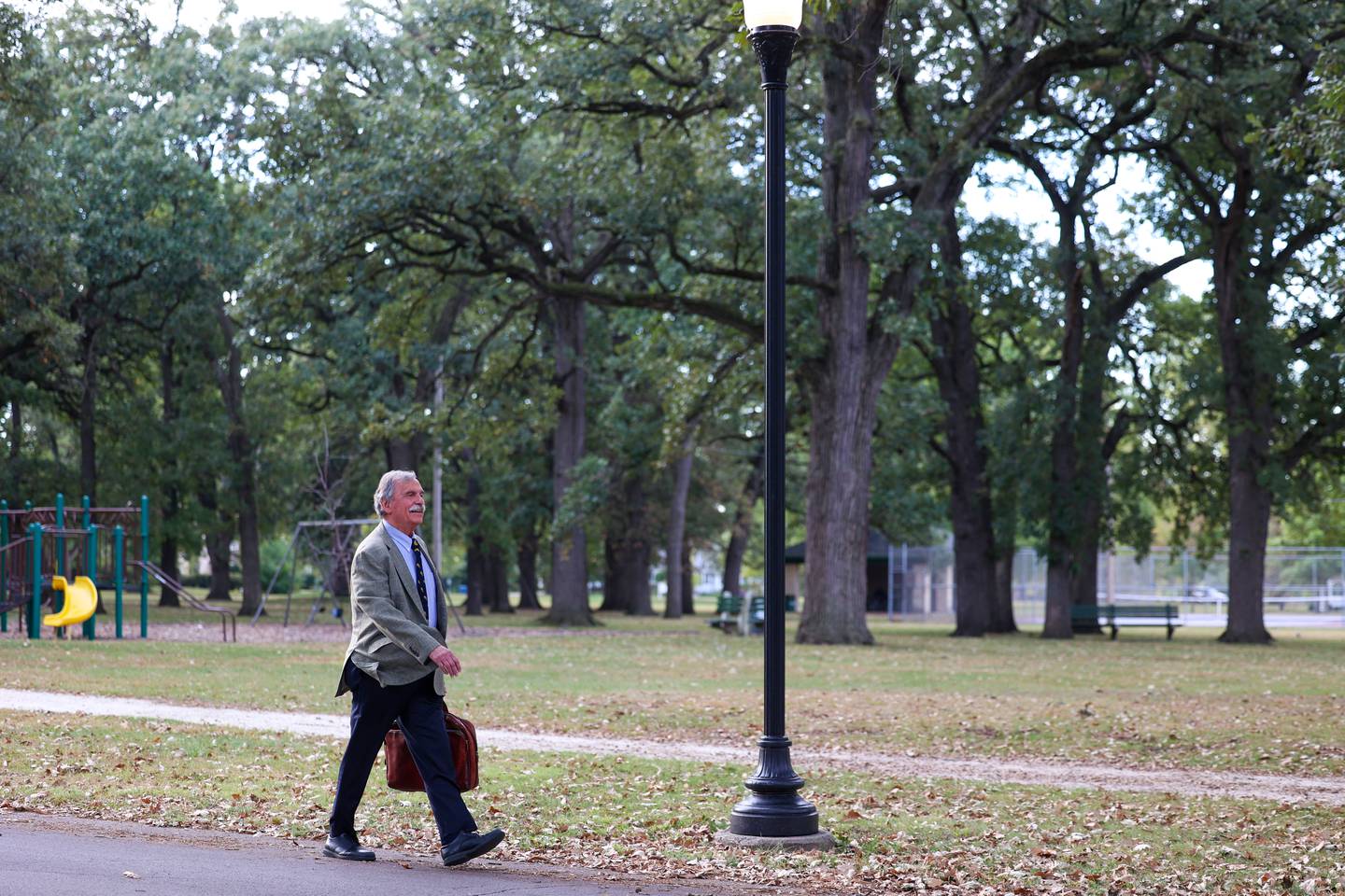 Dennis Baron walks past Cobb Park on his way to his last day of work on Oct. 10, 2025.