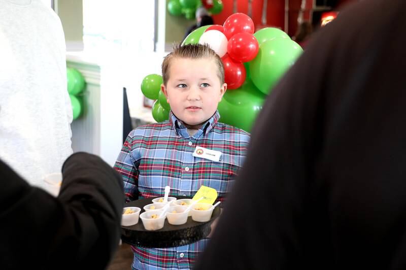 Graham Seaman, 9, hands out samples of chicken salad to those waiting in line at the new Chicken Salad Chick franchise, owned by his parents Garrett and Kim Seaman, during the store’s grand opening at 220 N. Randall Rd. in Batavia on Tuesday, Jan. 10, 2023.
