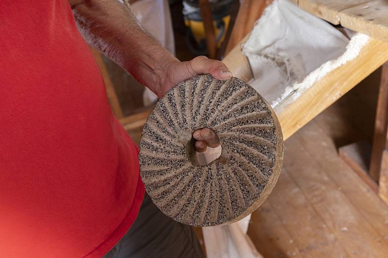 The 2,600-pound grinding wheel is made of blue basalt. Russell displays a small sample Friday, June 7, 2024.