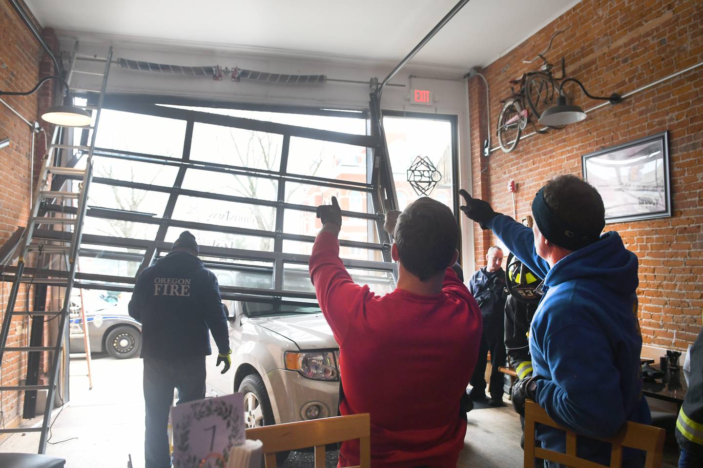 Dan and Mark Gale, of Oregon, talk with firefighters as they examine a vehicle that crashed into the Ogle County Brewery in downtown Oregon early Sunday afternoon after being struck by another vehicle at the intersection of Illinois 64 and Illinois 2.