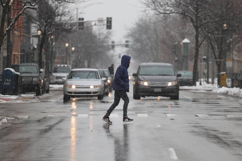 A mix of rain and snow falls in Joliet as a pedestrian crosses North Ottawa Street on Wednesday January 25th, 2023.