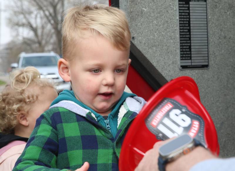 Hudson Schalk of Ottawa, receives a fire hat from Ottawa firefighters during story time on Thursday, April 10, 2025 at the Reddick Library in Ottawa. Kids were read a story by firefighters and got to check out a fire engine after.