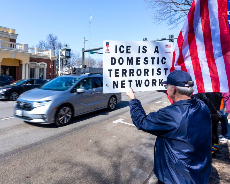 Protester holds sign as cars drive down La Salle St. during the 'Pretti good time for a Protest' on Feb. 15, 2026 at Washington Square Park in Ottawa.