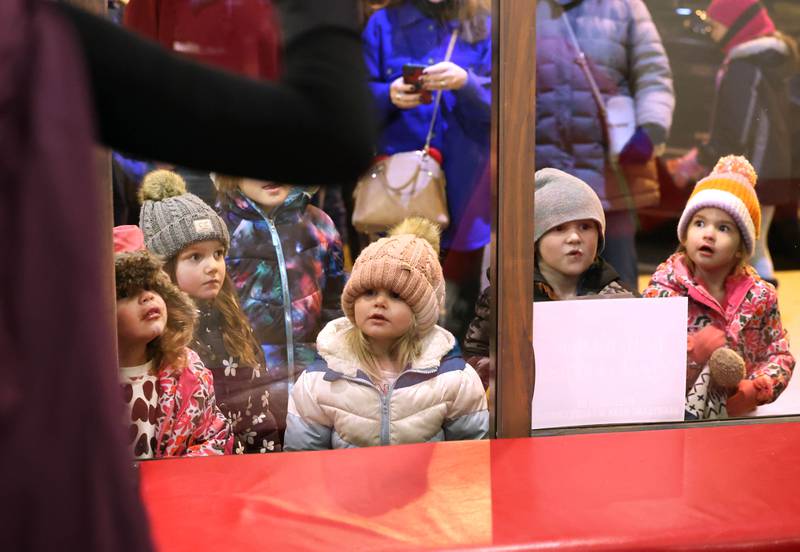 Kids peer through the window of Pizza. Beer. Whiskey. to watch a scene from “The Nutcracker” play out Friday, Nov. 22, 2024, during Moonlight Magic in downtown Sycamore.