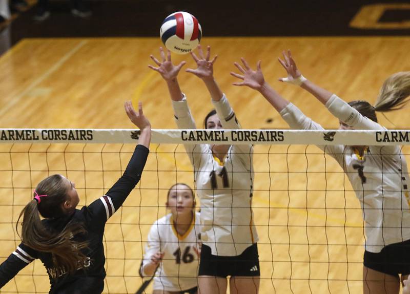 Prairie Ridge's Addy Grider (left) tips the ball over the block of Carmel’s Charlotte Shepherd (center) and Liv Johnson (right) during the IHSA Class 3A Carmel Sectional championship volleyball match on Thursday, Nov. 6, 2025, at Carmel High School, in Mundelein.