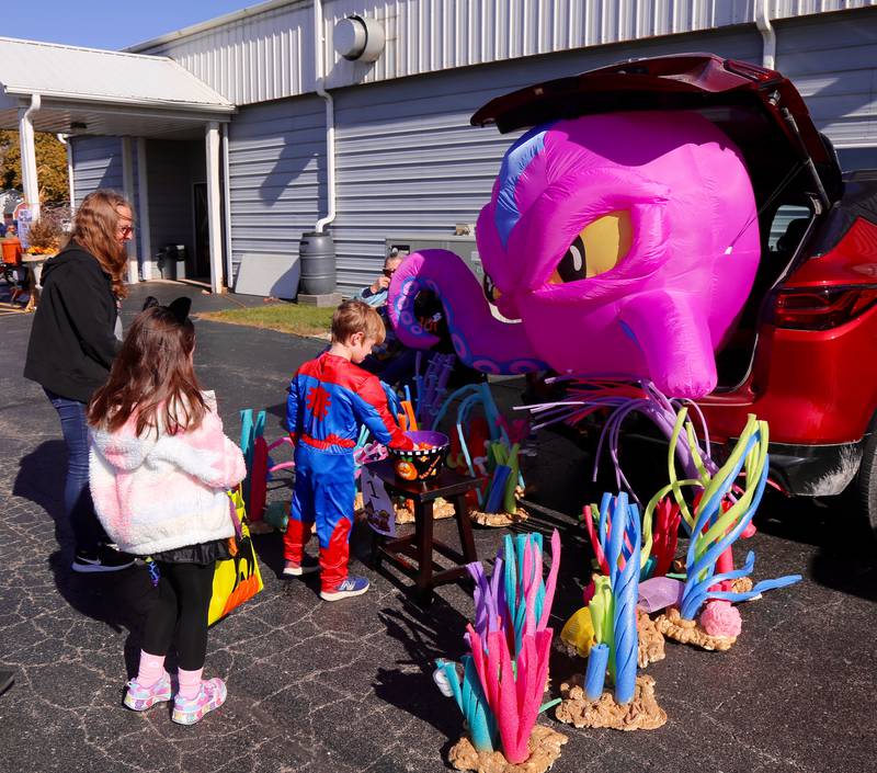 Leo Vilumis and Arianna Arroyo get a treat from Denise Lualhati of Pavilion Healthcare at the Fox Valley Family YMCA West branch Trick or Trunk on Sunday, Oct. 26, 2025 in Sandwich.