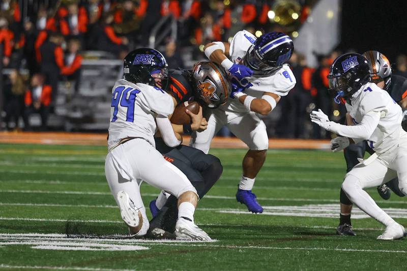 Lincoln-Way East’s Charlie Cosich (94) and Miko Moraga (9) brings down Minooka’s Zane Caves on Friday, Nov. 8, 2024 in Minooka.