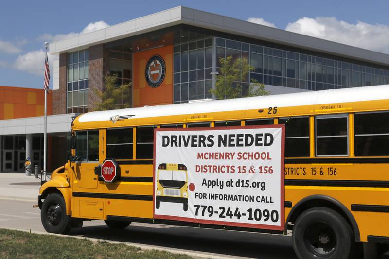 A drivers wanted sign is hung on the side a parked school bus in front of Upper Campus of McHenry High School on Thursday, July 27, 2023.