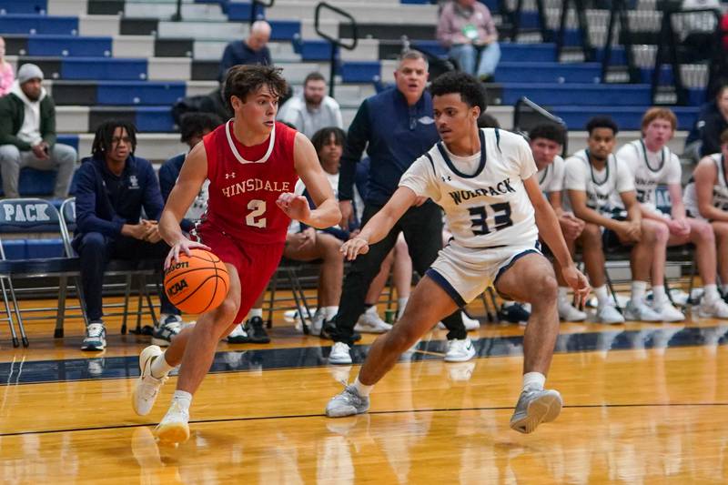 Hinsdale Central's Dillon Orozco (2) drives the baseline against Oswego East's Michael Rembert (33) during a hoops for healing tournament basketball game at Oswego East High School on Tuesday, Nov. 26, 2024.