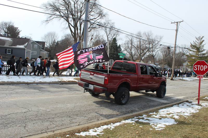 Crystal Lake Central Students walk out of the school in a protest against ICE while a car passes by with a Trump flag on Feb. 9, 2026.