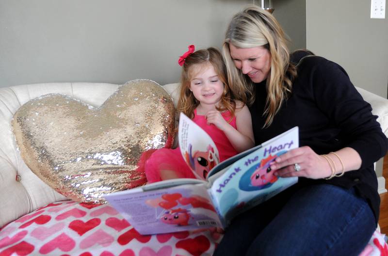 Everly Backe, 4, who has had multiple open heart surgeries to correct congenital heart defects, reads a book Friday, Feb. 11, 2022, with her mother, Lauren, in their Crystal Lake home. As Everly has became more aware of her chest scar, which they call her "zipper," her dad, Matt, recently decided to get a tattoo that matches his daughter’s scar from her surgeries so she does not feel alone in having the scar.
