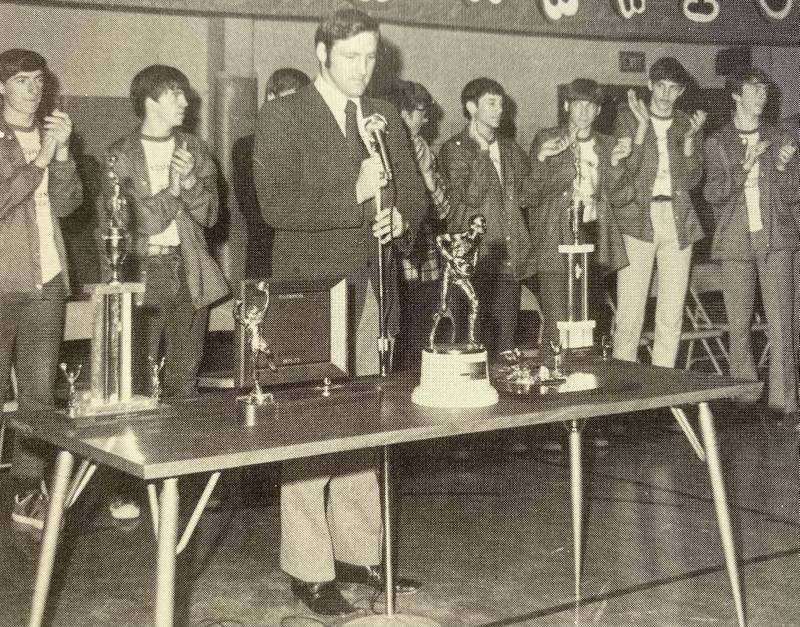 Backed by his 1971-72 Warriors, Woodland boys basketball coach Jerry Ross speaks at an assembly about the team's run to the Class A Elite Eight.