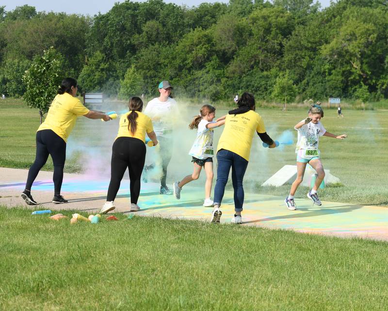 Zadie Koehler (right) Adalyn Manheim (middle) and Samantha Koehler, all from Sycamore, get sprayed with color powder on Saturday, June 7, 2025, during the CASA DeKalb County 5K Color Run held at the Sycamore Middle School.