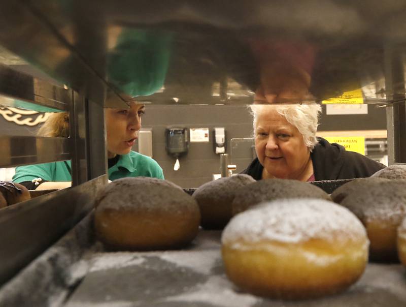 Natalia Chemerys, who works in the bakery department at Deli 4 You in Algonquin, helps  Judy Cleary of Lake in the Hills select paczki Wednesday, Feb, 15, 2023. Area bakeries are prepping for the lead-up to Lent when paczki are traditionally eaten. Deli 4 You will make and sell around 30,000 paczki this week.