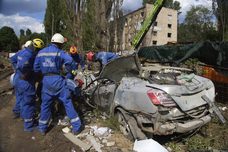 Emergency workers inspect a damaged car close to the multi-storey residential house that was ruined by a Russian missile Thursday night, killing 31 civilians including five children, in Kyiv, Ukraine, Friday, Aug. 1, 2025. (AP Photo/Efrem Lukatsky)