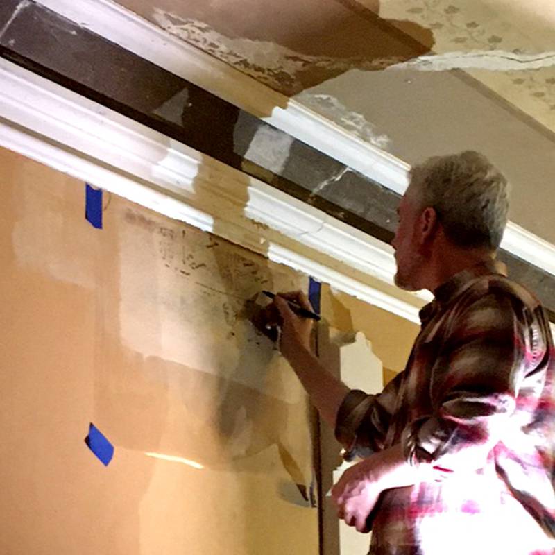 Restoration expert Anthony Kartsonas working to reveal original design elements in the Ellwood mansion's second floor hall.